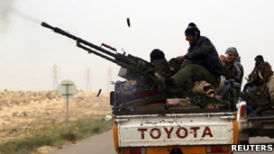 Libyan rebel fighters fire artillery as they flee from pro-Gaddafi forces