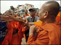 Một người đang cố gắng ngăn chặn hai nhà sư ẩu đả lẫn nhau