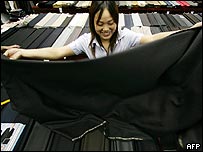 Čínská dělnice přeměřuje látku na šaty