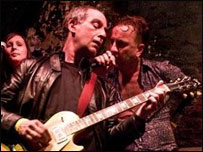 Loyd Grossman playing guitar for The New Forbidden