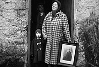 'Chwalfa'r Garnedd Lwyd - Mrs M K Morgan a Leslie Hughes, gydag Efan Jones yn ochneidio yng nghysgod y drws'. (Drwy garedigrwydd Llyfrgell Genedlaethol Cymru - casgliad Geoff Charles).