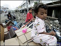 کودک آچه ای در انتظار والدين اش که در جستجوی چيزهای سالم مانده در خانه ويران شده خودند