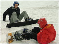 Two people trying to snowboard