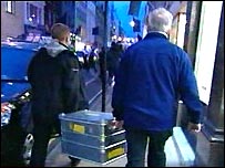 Policiais carregam material para ser analisado