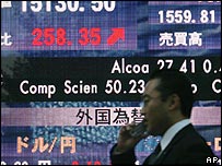 يک مرد ژاپنی از مقابل تابلو الکترونيکی اطلاعات بازار سهام عبور می کند