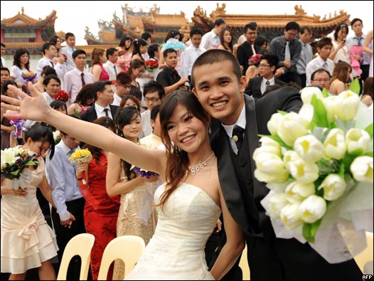 马来西亚吉隆坡天后宫集体婚礼上一对新人向镜头展示灿烂笑容(9/9/2009)