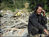 Homem chora perto de destroços em Sichuan (15/05)