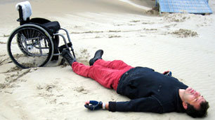 Tim Rushby-Smith lying on the ground in front of his wheelchair, trying to use his special powers to get up again