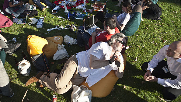 Folk chat on a sunlit lawn, surrounded by tents. And computers. And cables.