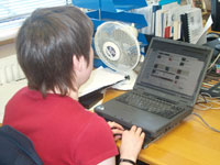 Liz Ball reading a website on her laptop, using a Braille display