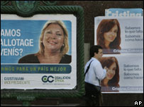 Homem passa por cartazes das candidatas Elisa Carrió e Cristina Fernández de Kirchner em Buenos Aires