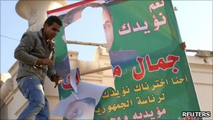 Protestors in Alexandria deface posters of Hosni Mubarak