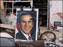 Pôster de Bush em Khiam, no sul do Líbano, enfeitado com sapatos e armas de brinquedo Foto: Martin Asser, 2006