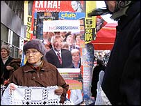 Chorvatka prodávající suvenýry před volebním plakátem