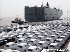 New cars, covered with white protection sheets, wait to get loaded onto transport ships at the Volkswagen car factory Emden on 24 April 2009