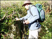A walker inspects a standing stone near Cleveley 