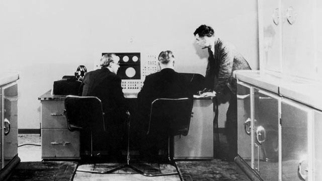 Alan Turing with two colleagues and a Ferranti computer in January 1951. Turing had previously been involved with the construction of both the Colossus and, later, the Automatic Computing Engine.