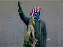 Soldado americano coloca bandeira americana sobre estátua de Saddam Hussein 