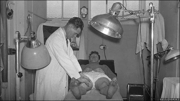 Team trainer Jimmy Trotter works on a player under radiant heat lamps for bruised muscles at the Charlton Athletic in 1939