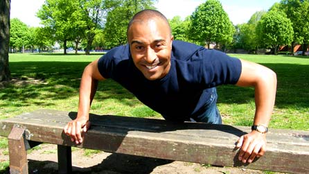 Colin Jackson performing a push-up on a park bench