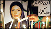 An Iranian, wearing a green ribbon on her arm, lights a candle in front of a picture of Neda Agha-Soltan