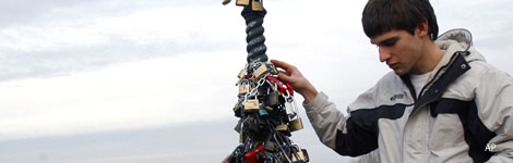 A man attaching padlocks to a bridge