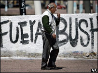 Homem passa em frente a muro com slogan "Fora Bush"