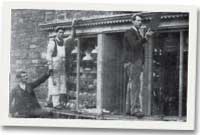 Ddoe - David Davies yn gwylio gweithwyr yn rhoi plwm newydd uwchben ffenest y siop.