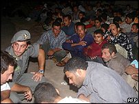 Italští policisté pomáhají žadatelům o azyl na ostrově Lampedusa