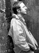 A black and white photo of Alan Spence leaning against a wall