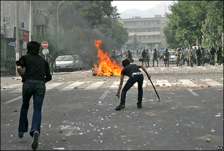 Supporters of opposition leader Mir Hossien Mousavi set fire to a barricade as they hurl stones at riot police during a protest in Tehran on Saturday June, 20, 2009