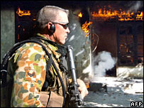 Soldado australiano passa em frente a casa incendiada na capital, Dili