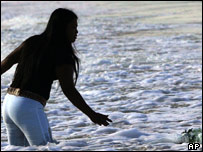 Tailandesa joga flores no mar, na praia de Patong, em Phuket, Tailândia
