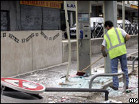 Homem limpa destroços de cabine telefônica destruída por manifestantes em Paris