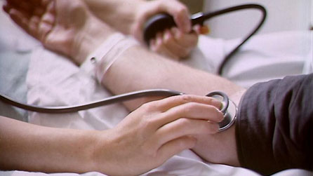 Doctor yn mesur pwysau gwaed claf.