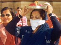 Worshipper, bearing an offering on her head and walking around the images