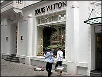 Những người bán hàng rong đi ngang qua cửa hàng đồ hiệu Louis Vuitton 