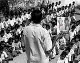 Photo of a man showing children a picture of baby with smallpox