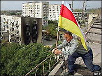 Evinin çatısına Güney Osetya bayrağı diken bir adam