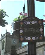 Flower baskets in Bedworth with All Saints church in background 