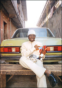 A young man with a copy of Focus on Africa magazine next to a Mercedes