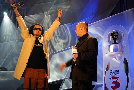 Wojciech Krzak from the Warsaw Village Band accepts their award from Scottish violinist John McCusker