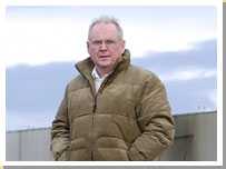 Photograph of George Cunningham with part of the former Linwood car factory in the background.