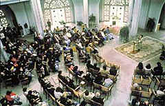 Worship meeting in a large, light room with chairs arranged around a central speaker