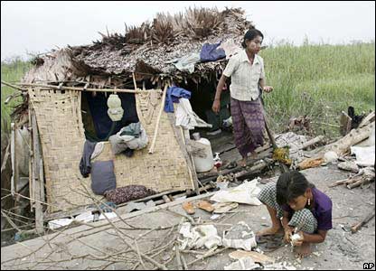 People outside a damaged house on the outskirts of Rangoon