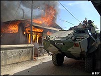 Tropas da Malásia passam por casa incendiada