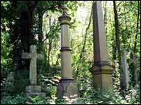 Trees and shurbs surround three headstones