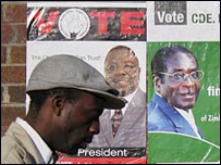 Một người đàn ông đi ngang qua poster bầu cử Zimbabwe