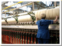Photograph of a woman working at a spinning machine in 2004.