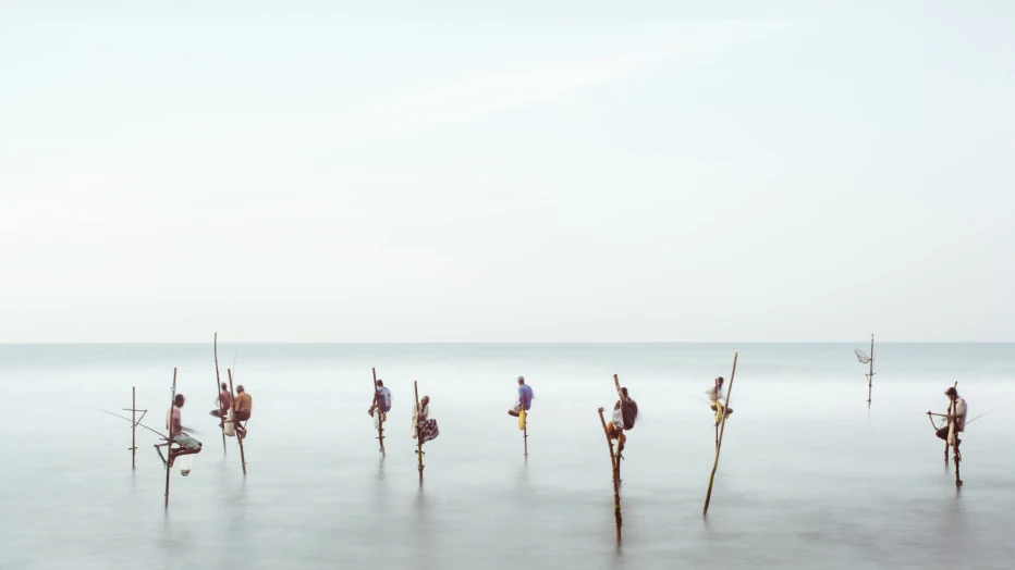 Men on fishing poles on the sea.